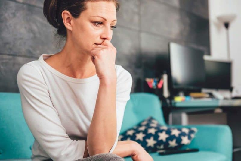 Concerned woman on couch, observing gut, GI, UC symptoms, inflammatory bowel disease symptoms