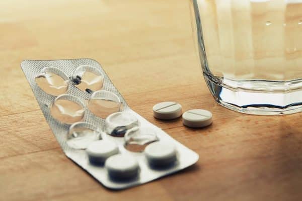 Anti-diarrheal tablets on table with glass of water to relieve diarrhea related to Crohn's disease or ulcerative colitis