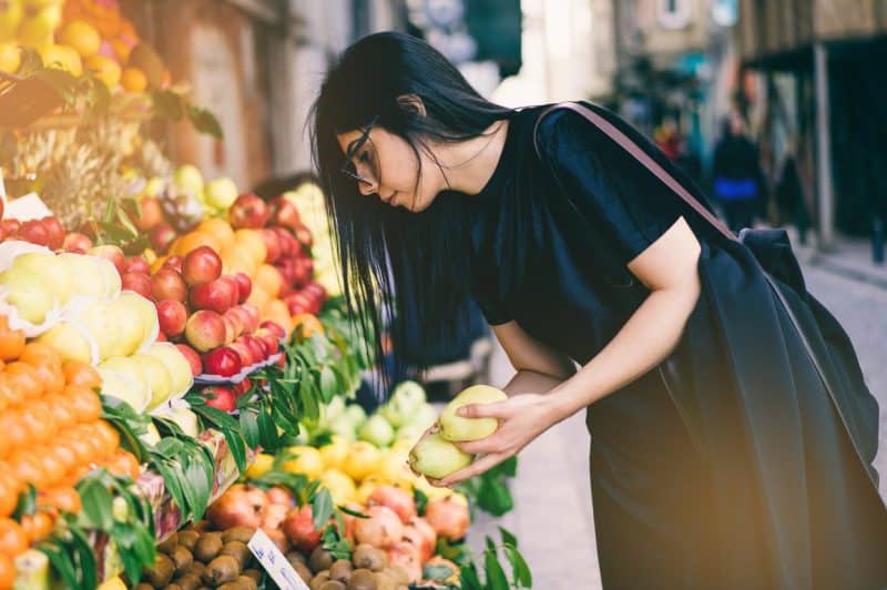 working with dietitian for ulcerative colitis diet, Woman buying fresh fruit from a farmer's market stand
