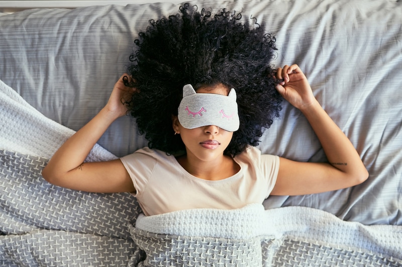 For more restful sleep with IBD, young woman sleeping in bed with mask